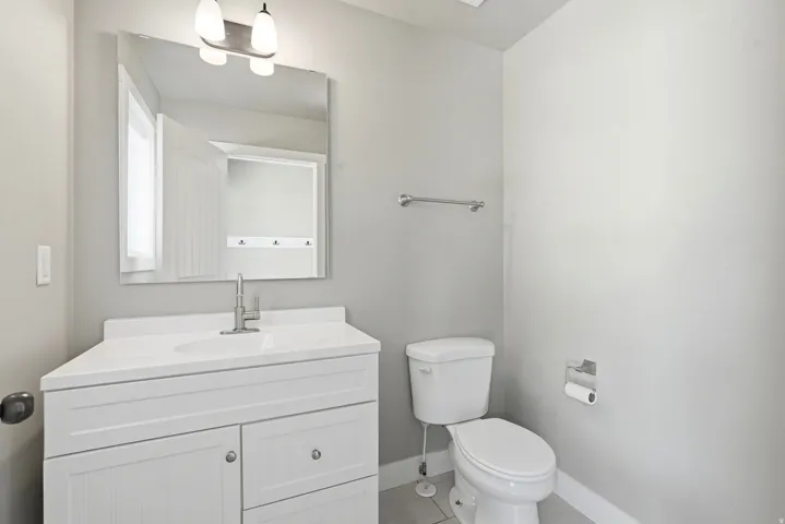 Bathroom featuring a white vanity with integrated sink, brushed nickel faucet, large wall-mounted mirror, and overhead lighting fixture