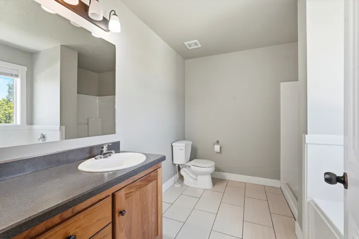 Vanity with a single basin sink, dark countertop, and wood-finish cabinetry