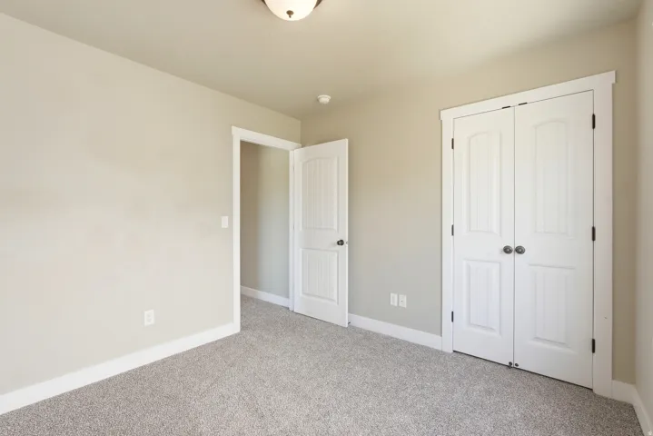 Neutral-toned room featuring a semi-flush mount ceiling light, light-colored walls, and gray carpeting