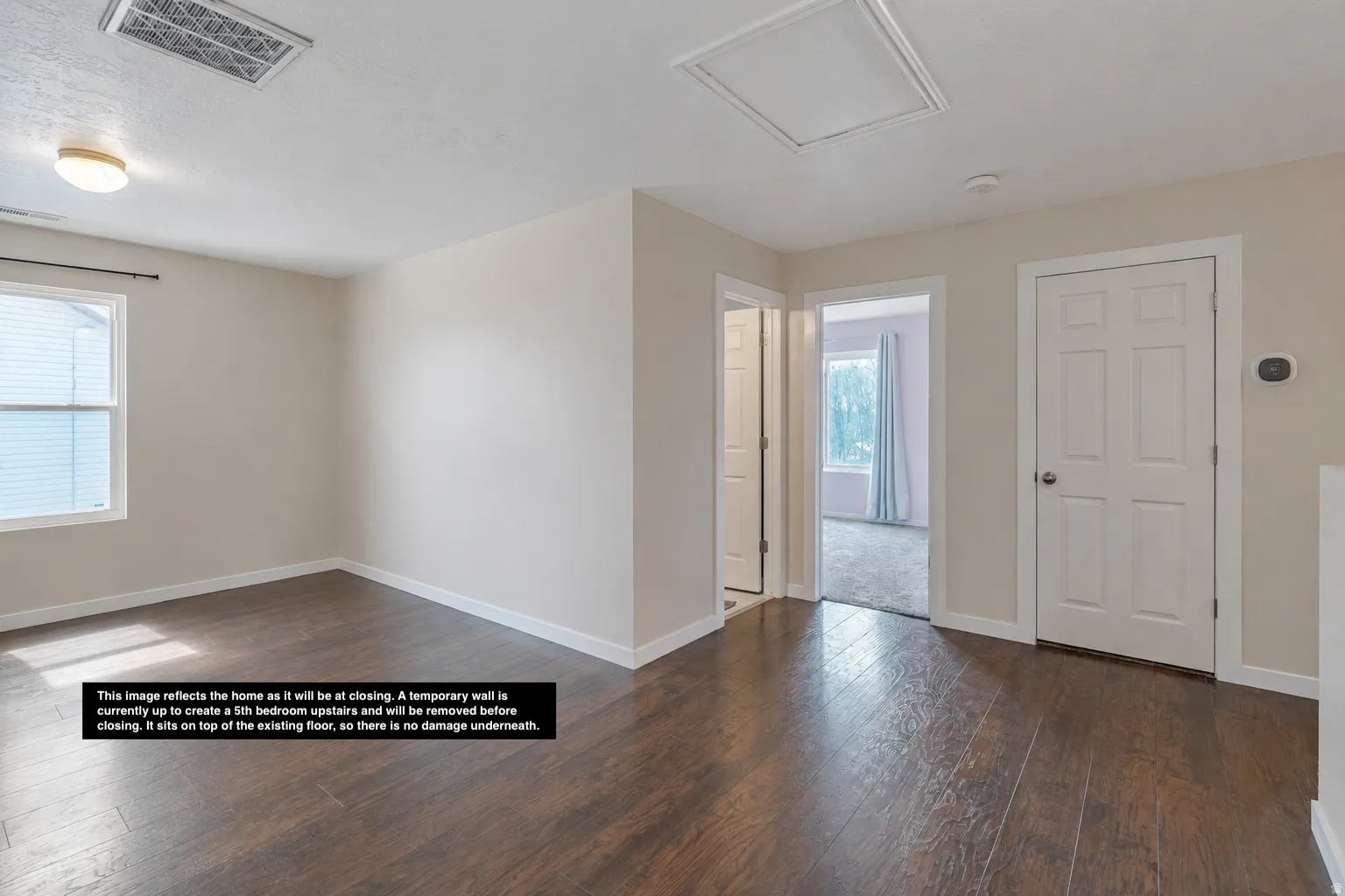 Spacious room featuring wood-finish flooring, neutral wall tones, and a double-pane window for natural light