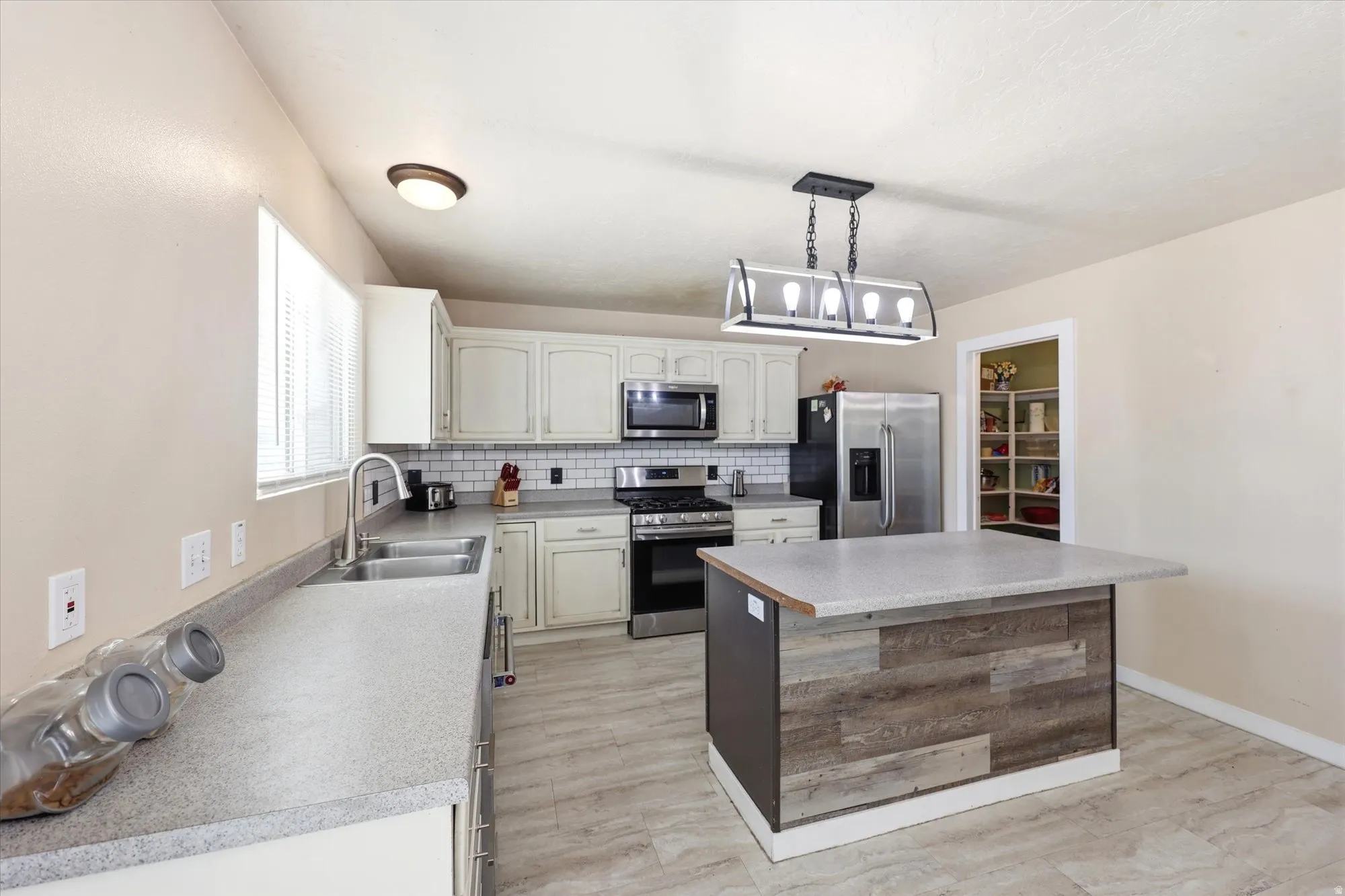 Kitchen featuring light-toned cabinetry, light countertops, subway tile backsplash, and wood-finish flooring