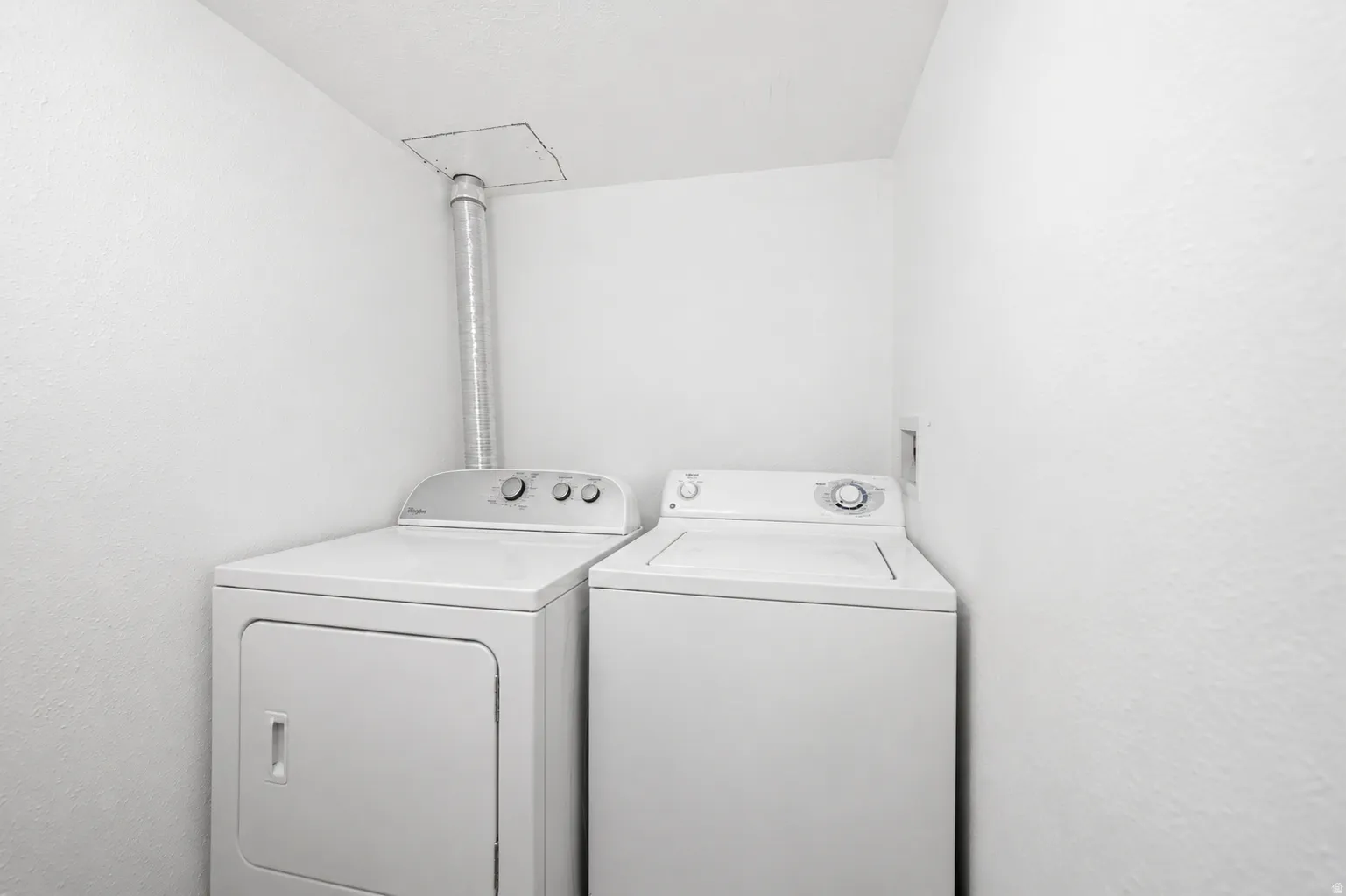 Dedicated laundry area with a white top-load washing machine and a white front-load dryer