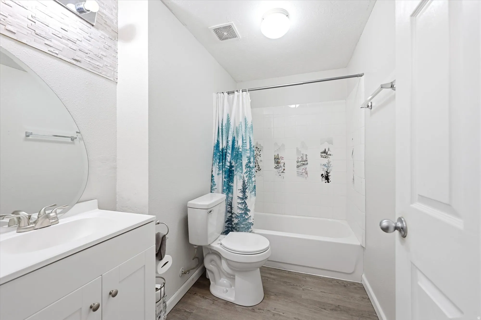 Full bathroom featuring a white vanity with integrated sink, brushed nickel faucet, and a round frameless mirror