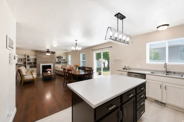 Open concept living area featuring wood-finish flooring, a fireplace with a light-toned wood-plank surround, and built-in shelving