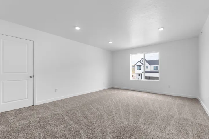 Spacious room featuring neutral carpeting, white walls, and recessed lighting