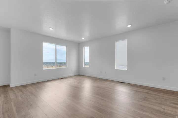 Spacious room featuring light wood-finish flooring, recessed lighting, and multiple windows