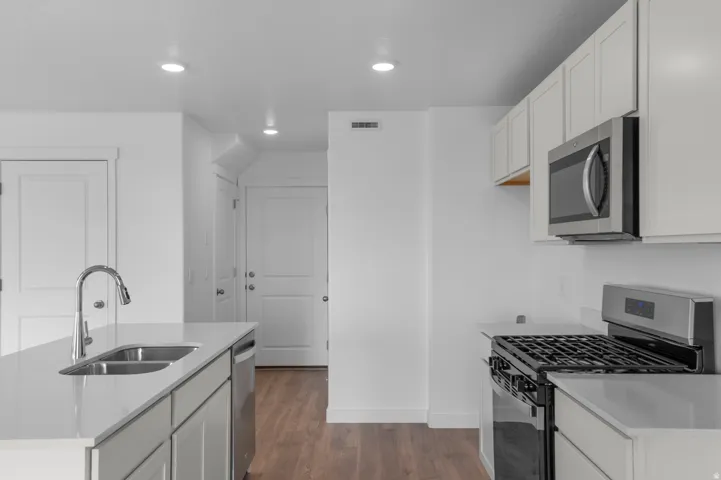 Modern kitchen featuring light cabinetry, stainless steel appliances, a gas range, and a double basin sink with a high-arch faucet