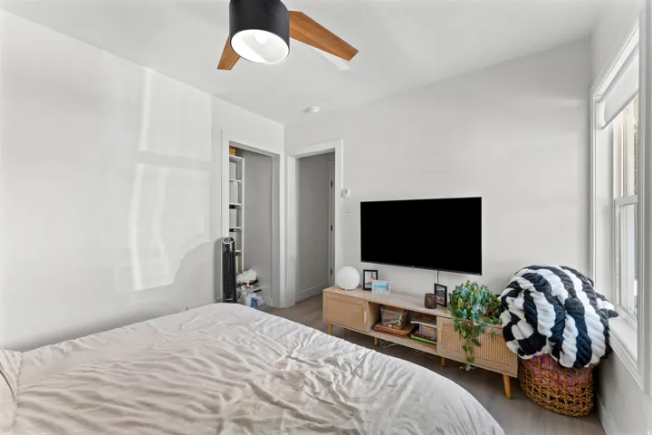White painted walls featuring a wood-finish floor and a window with white trim