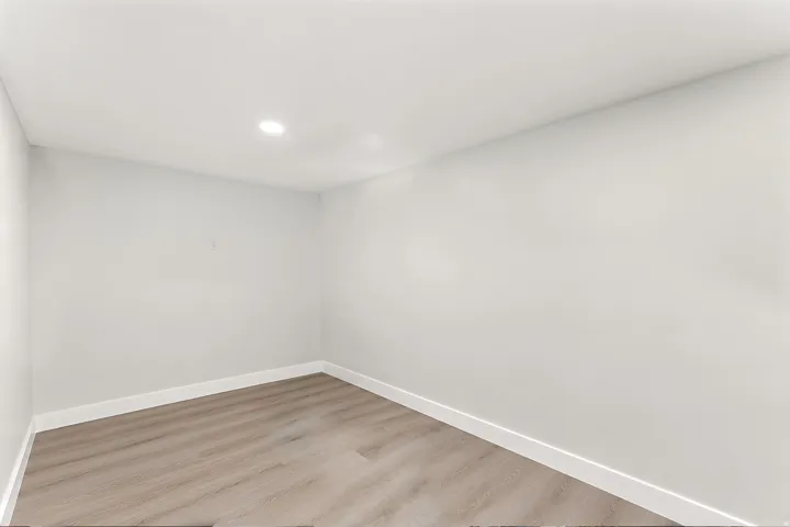 Crisp interior space featuring light-toned walls, wood-finish flooring, recessed ceiling lighting, and white baseboards