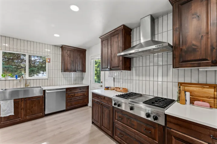 Kitchen featuring rich wood cabinetry, light wood-finish flooring, white countertops, and a white vertical tile backsplash
