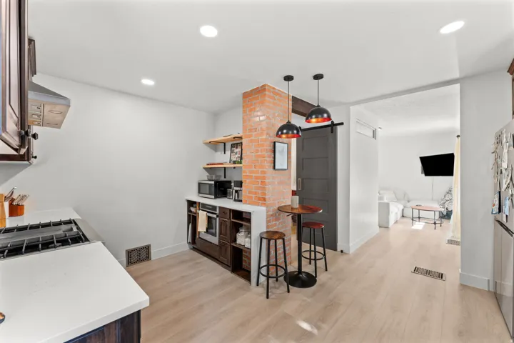 Modern kitchen featuring wood-finish flooring, white countertops, and dark wood-stained cabinetry