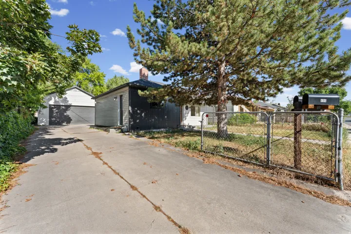 Long concrete driveway providing access to a detached garage and a separate shed with dark siding