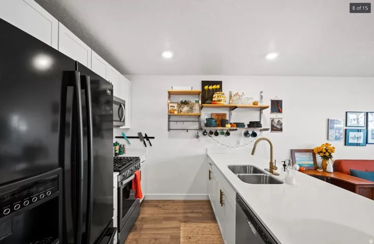 Modern kitchen featuring white cabinetry, a double basin sink with a bronze faucet, and a black French door refrigerator