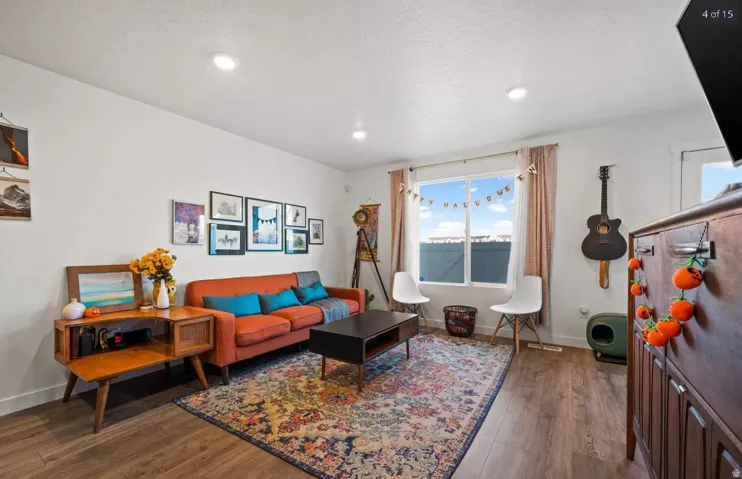 Spacious living area featuring wood-finish flooring, recessed lighting, and a large window providing ample natural light