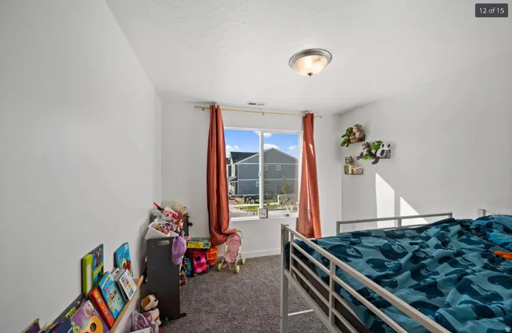 Room featuring a double window, ceiling-mounted light fixture, white walls, and gray carpet flooring