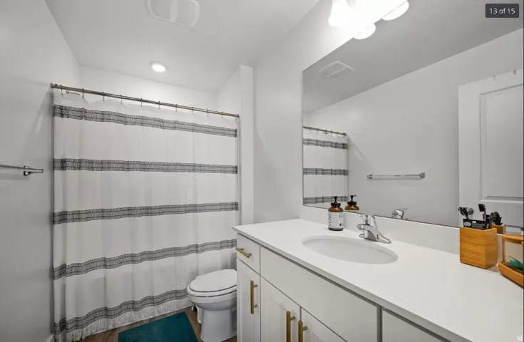 Bathroom featuring a white vanity with gold-tone hardware, a large vanity mirror, recessed ceiling lighting, a built-in exhaust fan, and wood-finish flooring