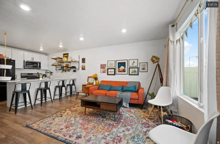 Open-concept living space featuring wood-finish flooring, recessed lighting, and a prominent window