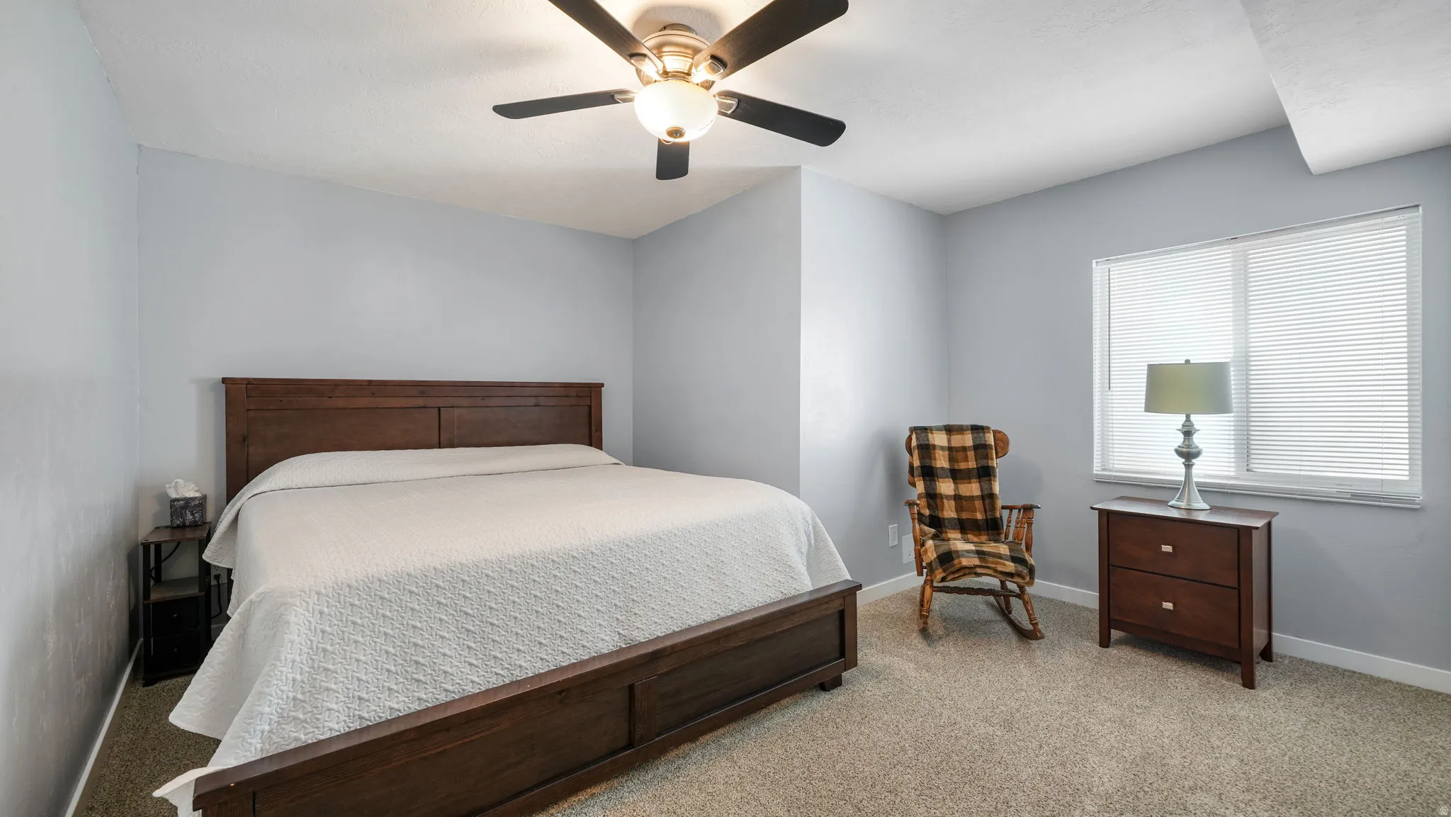 Carpeted room with a ceiling fan light fixture, light gray walls, and a window with blinds