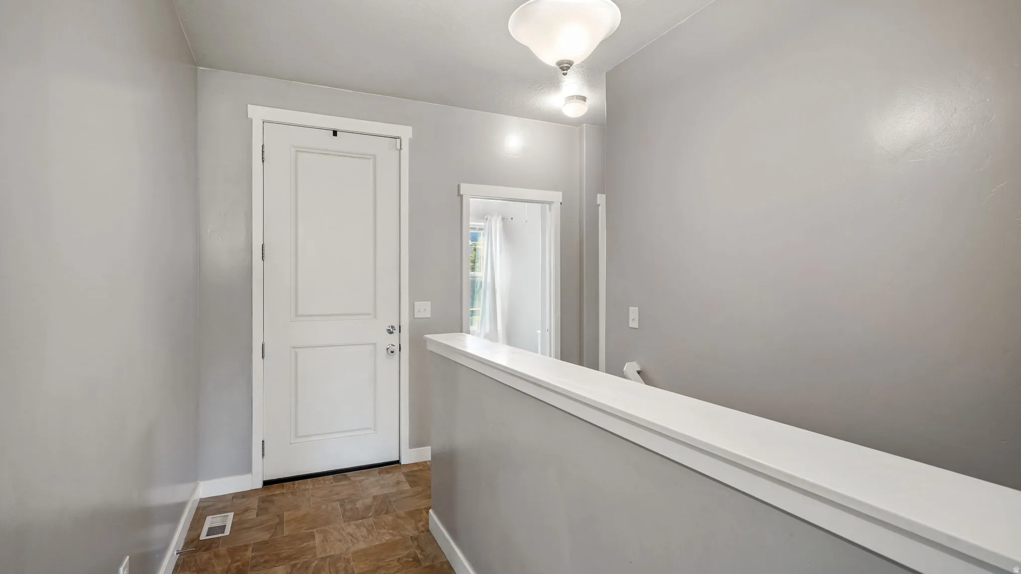 Entryway featuring a white paneled door, light gray walls, and brown patterned flooring