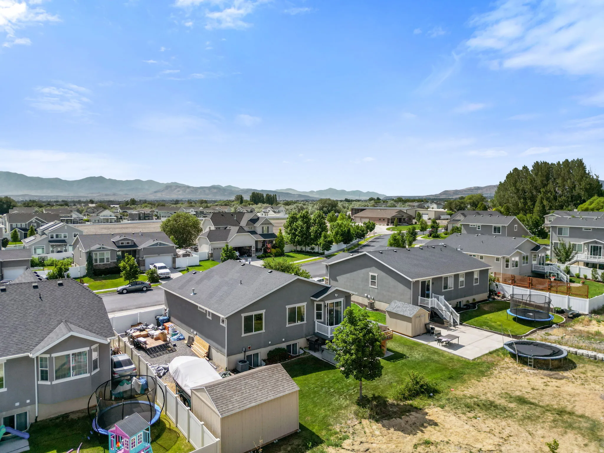 Expansive neighborhood showcasing multiple residential properties, mature trees, and mountainous scenery