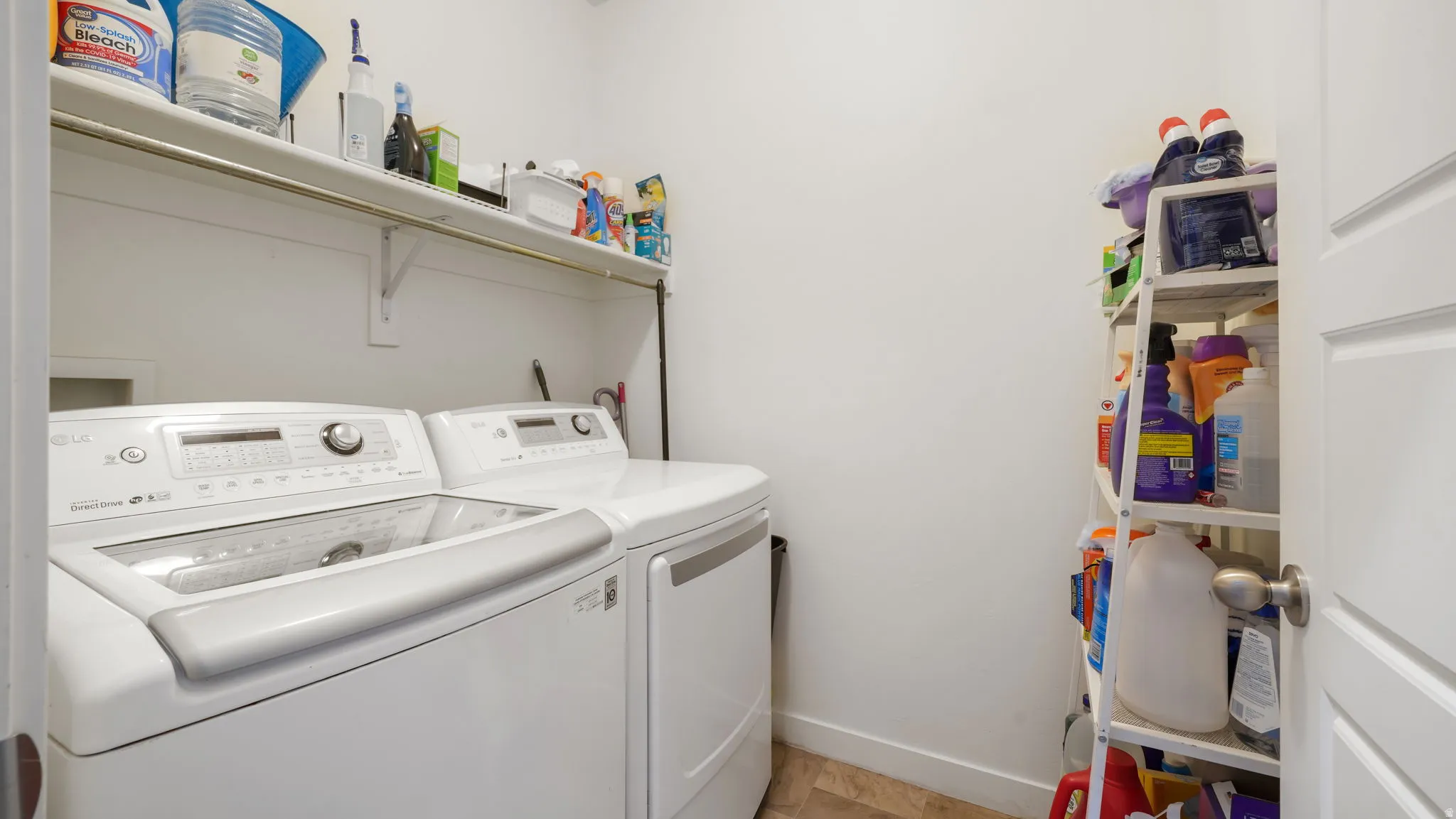 Dedicated laundry area featuring a washer and dryer, a wall-mounted shelving unit, and wood-finish flooring