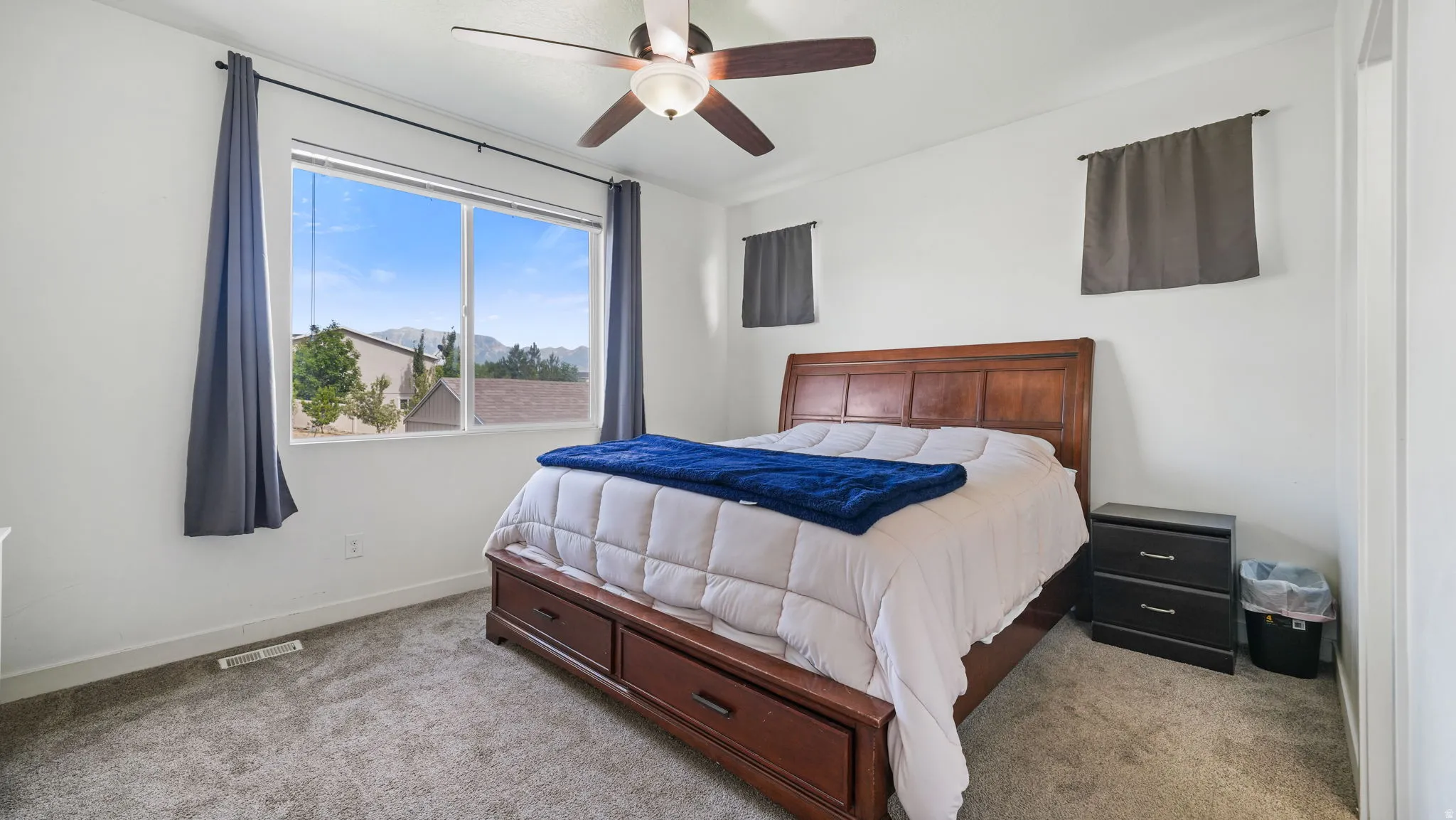 Carpeted room featuring a large window with mountain scenery and a ceiling fan