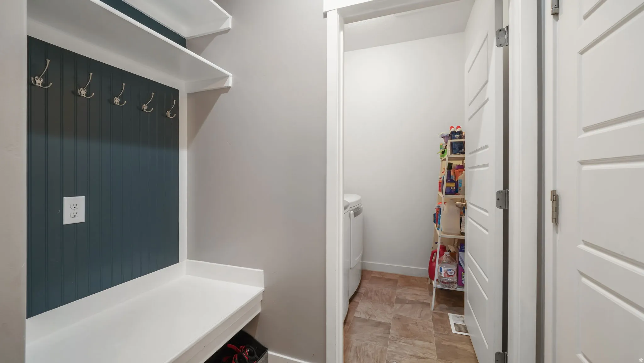 Built-in mudroom bench with white countertop, beadboard accent wall, and chrome coat hooks