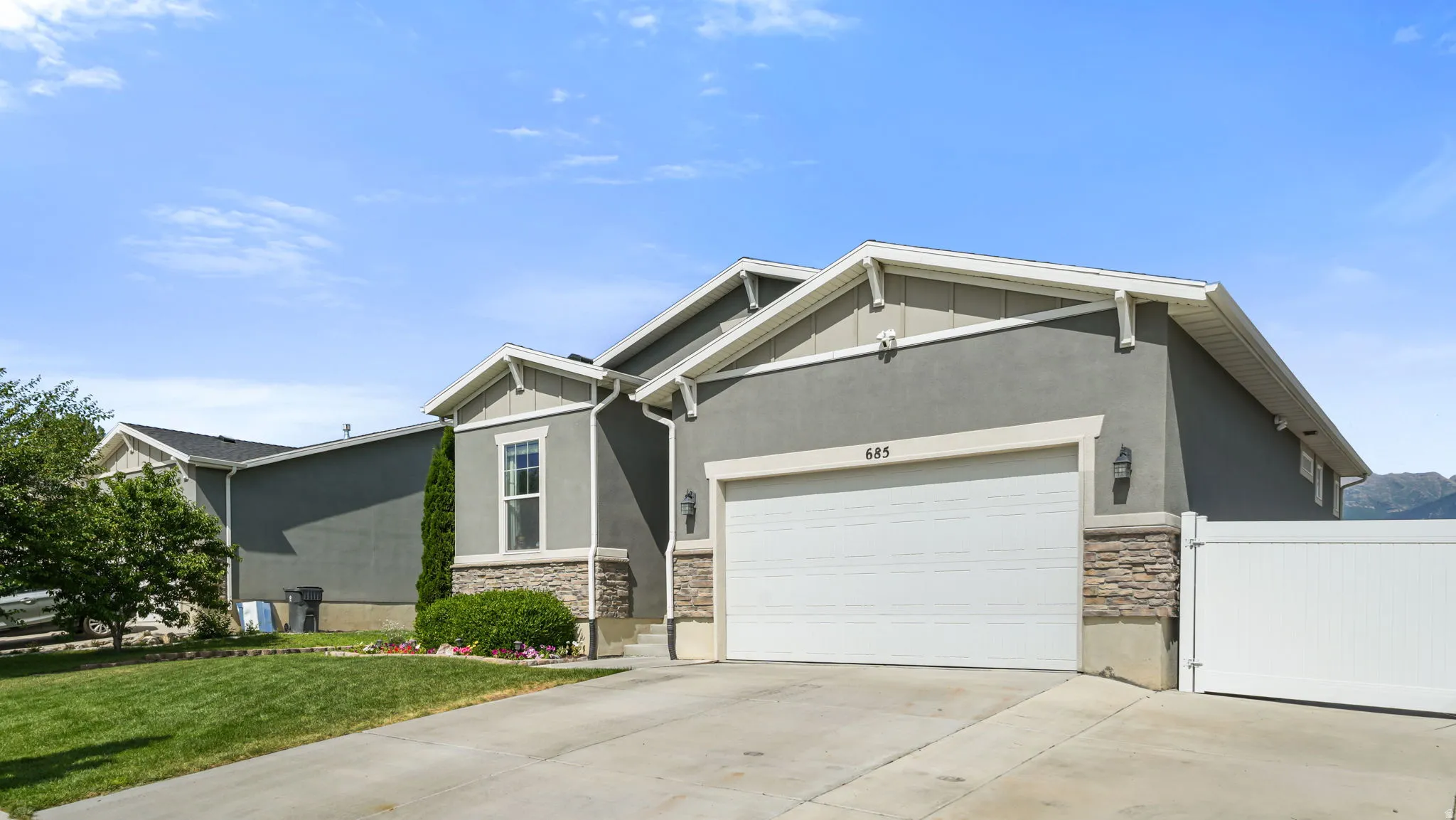Contemporary-style home featuring a gray stucco exterior with stone accents and white trim