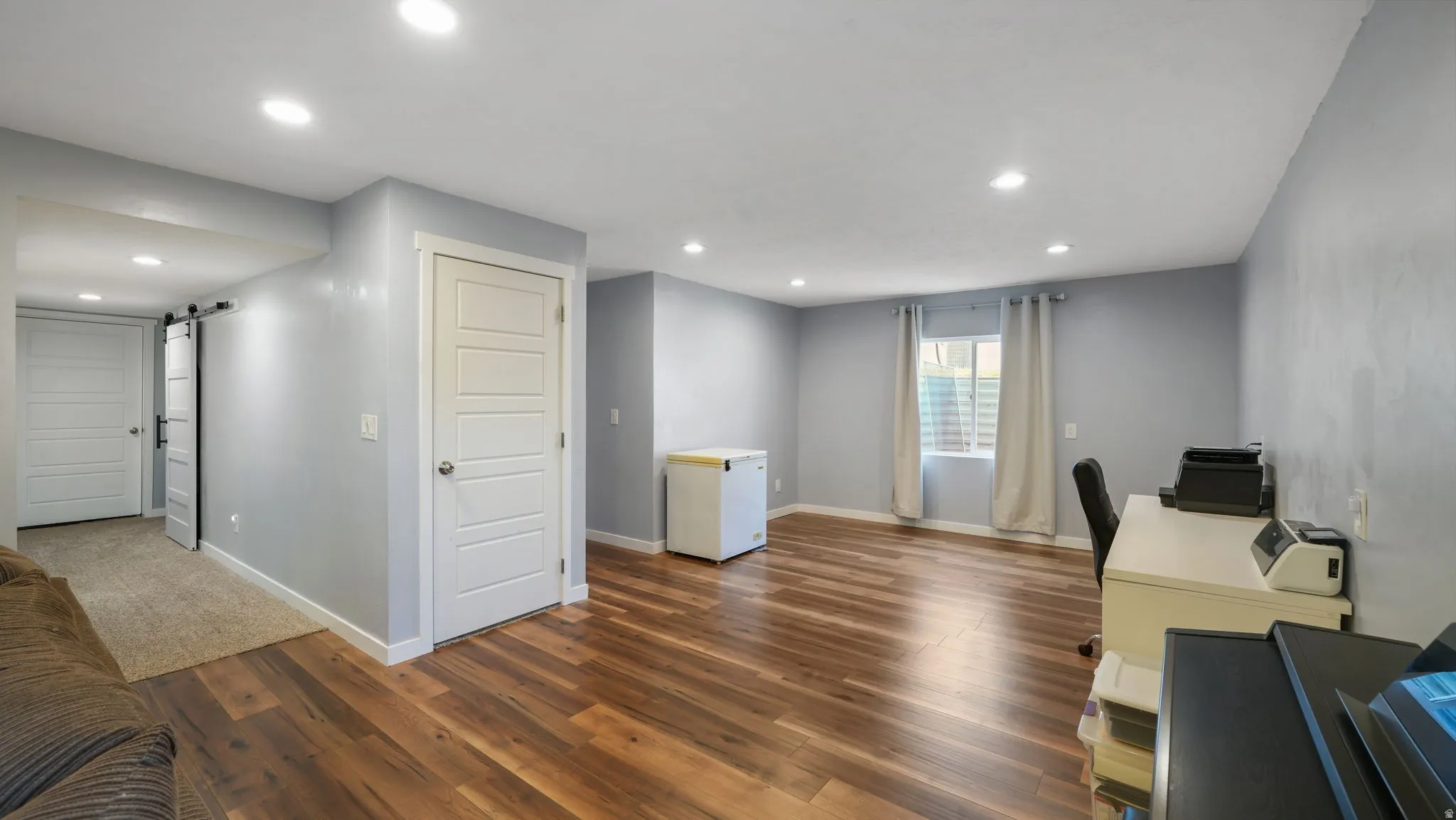 Spacious room featuring wood-finish flooring and recessed lighting
