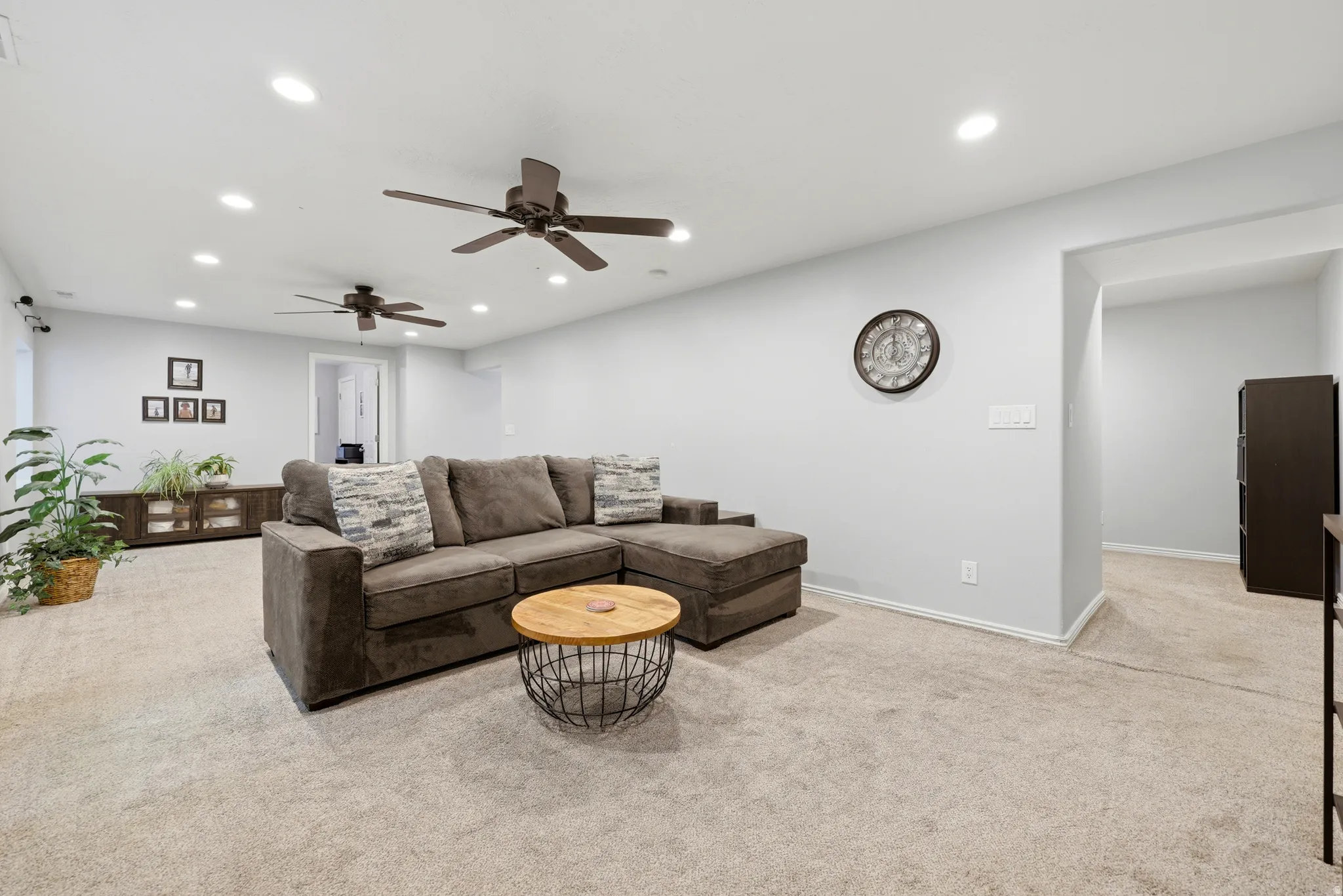 Spacious room featuring light-colored carpeting, recessed lighting, and two ceiling fans