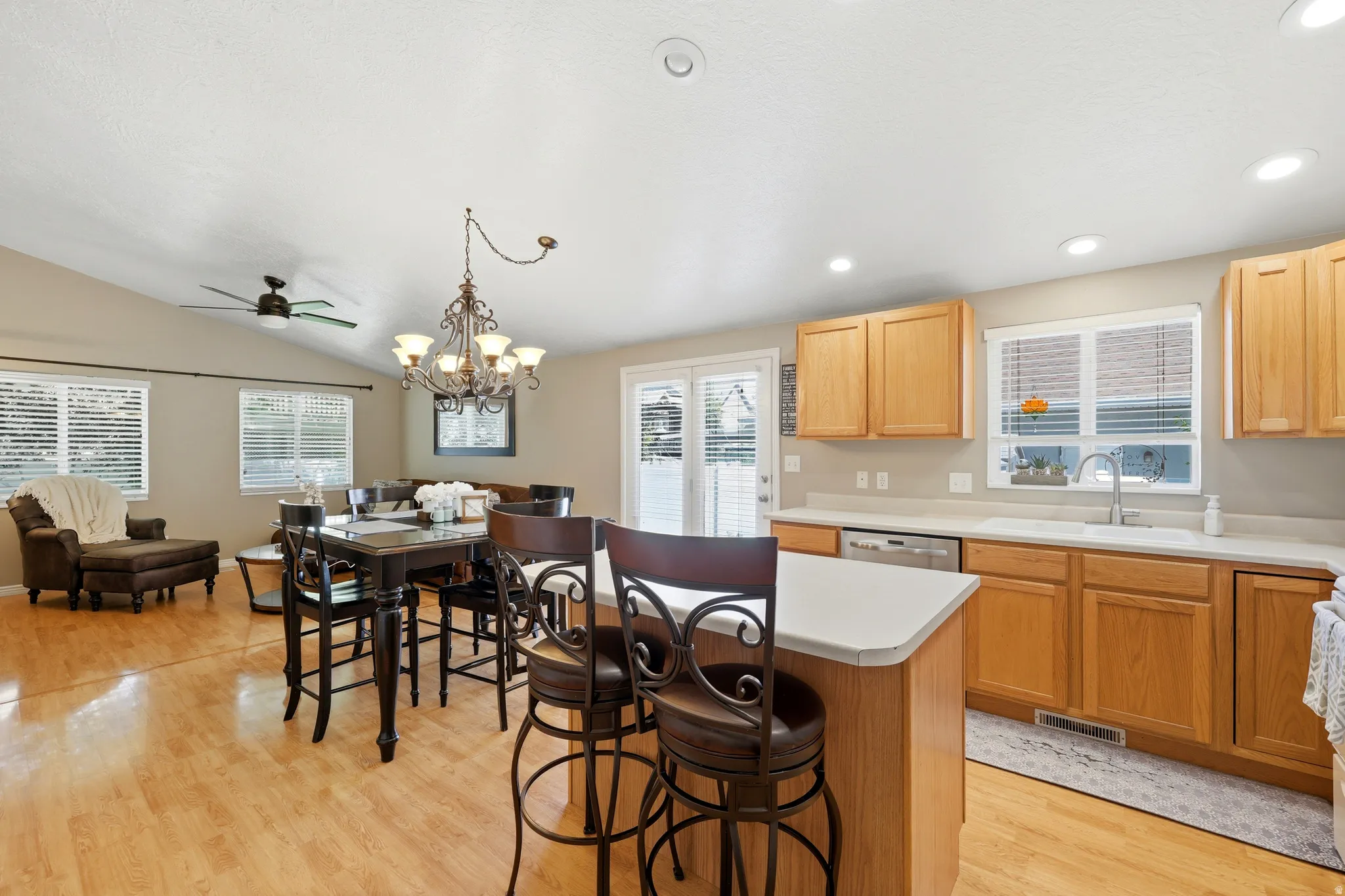Open-concept kitchen and living area featuring wood-finish flooring, vaulted ceilings, and recessed lighting