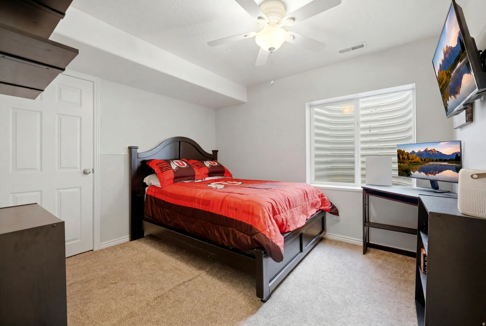 Carpeted room featuring a white paneled door, a white ceiling fan with integrated lighting, a well-window, and light gray wall paint