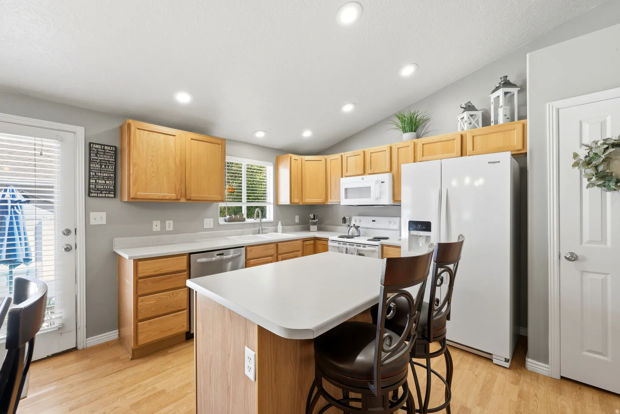 Kitchen featuring light wood cabinetry, white countertops, stainless steel dishwasher, and recessed lighting