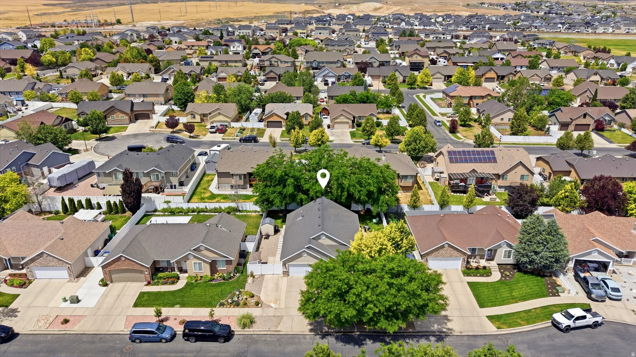 Suburban residence featuring a pitched roof, attached garage, paved driveway, and established landscaping