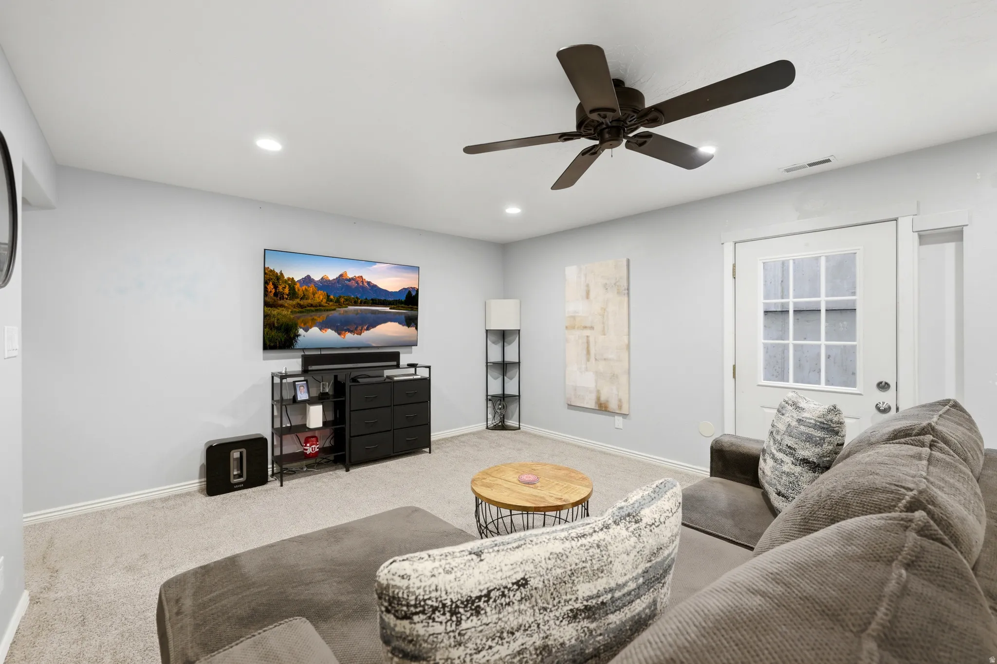 Carpeted living area featuring recessed lighting, a ceiling fan, and a white paneled door with windowpanes