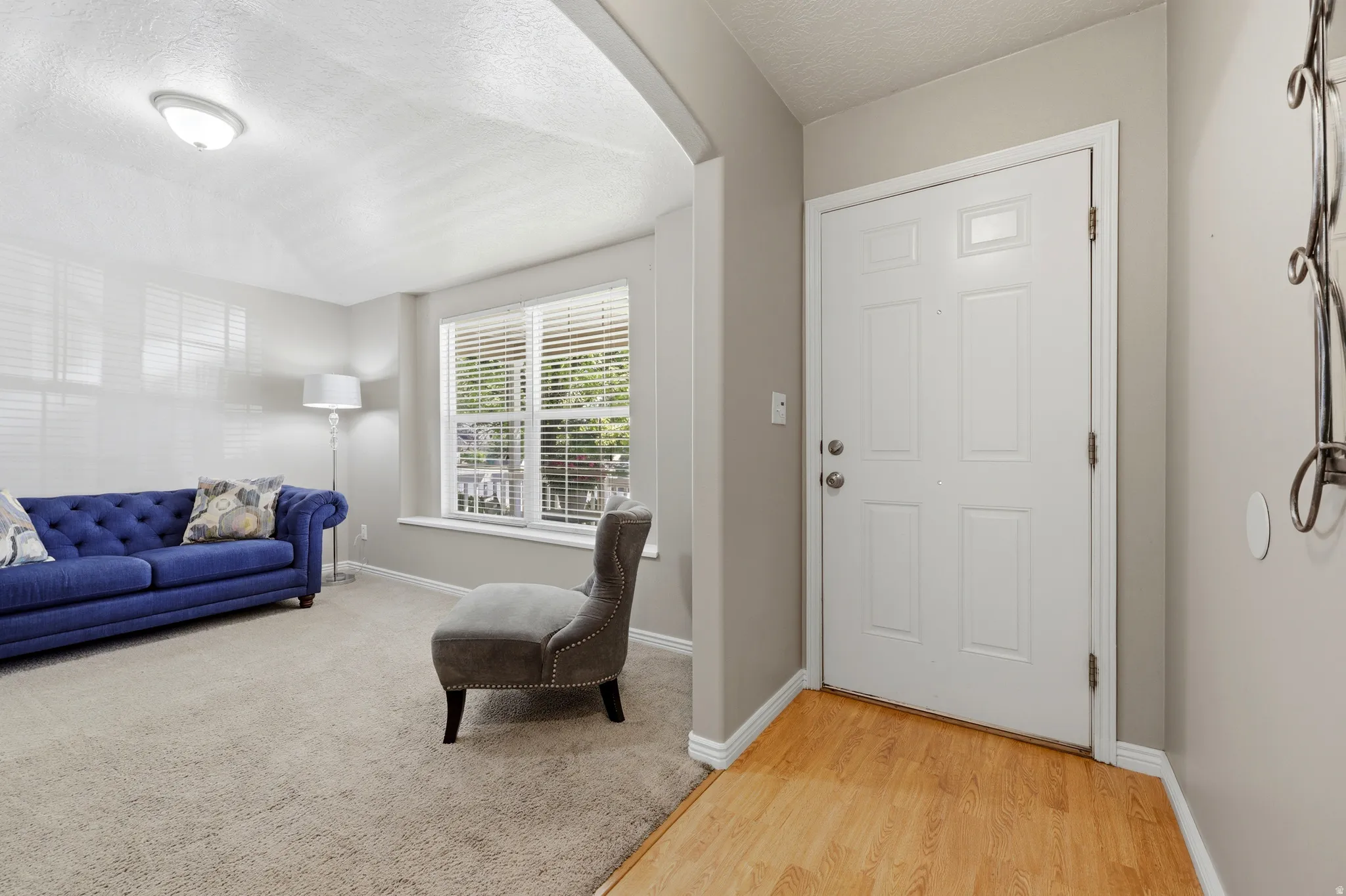 Entryway featuring wood-finish flooring transitioning to carpeted living space