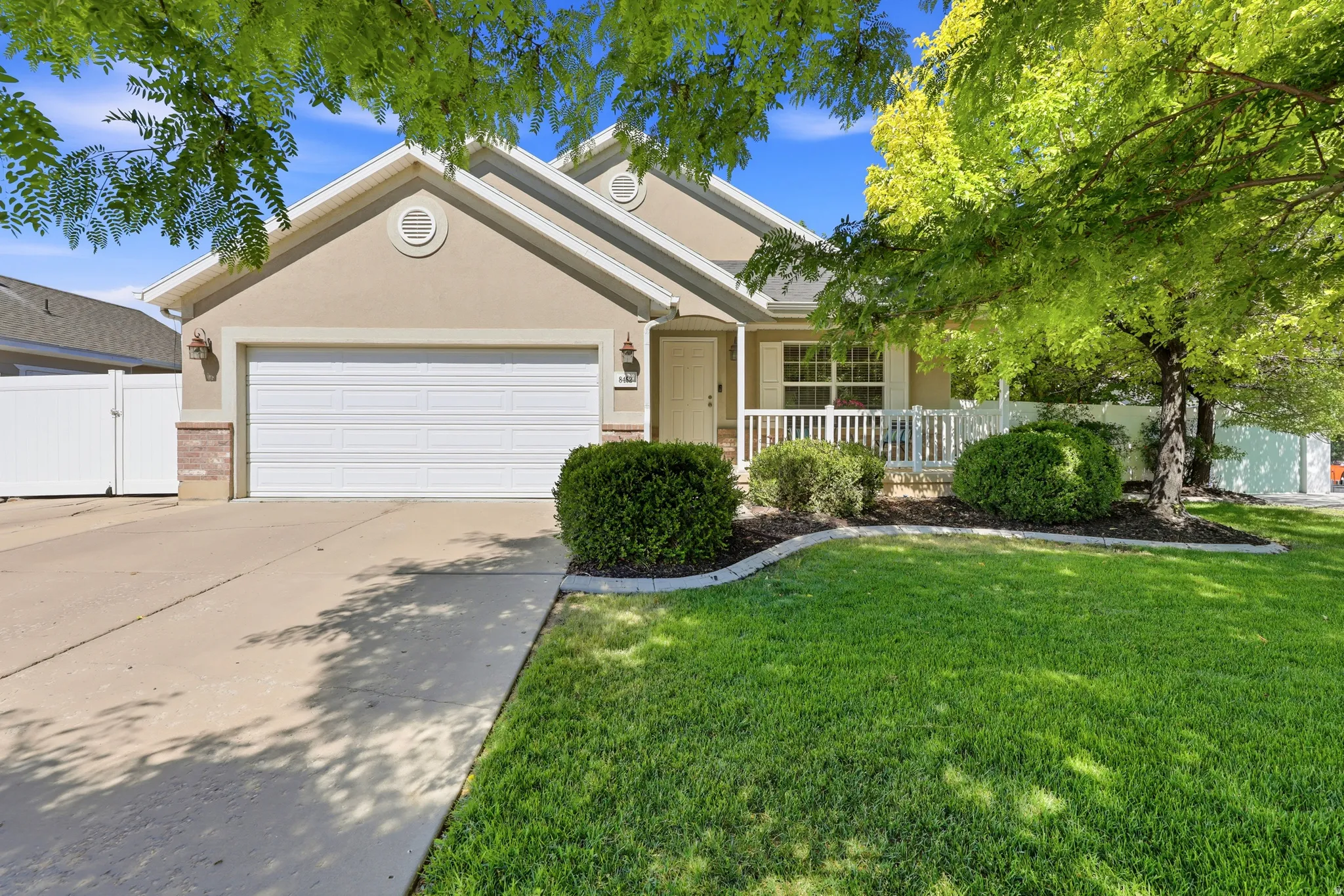 Ranch-style residence featuring a two-car garage, concrete driveway, and a front porch with white railing