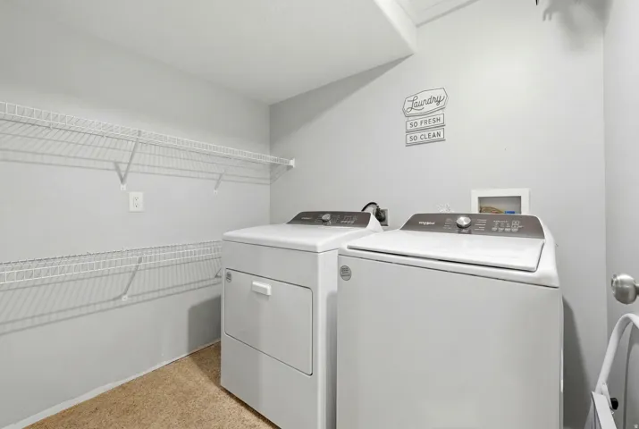 Dedicated laundry area featuring wire shelving, light grey wall paint, and beige textured flooring