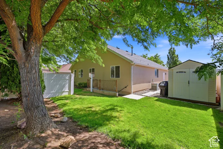Expansive backyard featuring a manicured lawn, established mature tree, and a storage shed