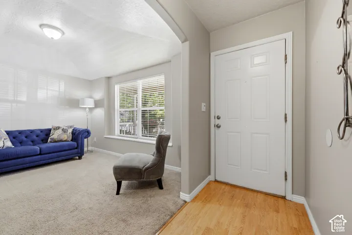 Entryway featuring wood-finish flooring transitioning to carpeted living space