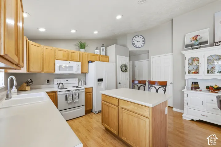 Kitchen featuring natural wood cabinetry, white countertops, a central island, recessed lighting, and wood-finish flooring