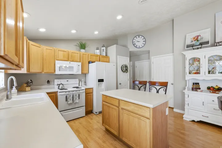 Kitchen featuring natural wood cabinetry, white countertops, a central island, recessed lighting, and wood-finish flooring