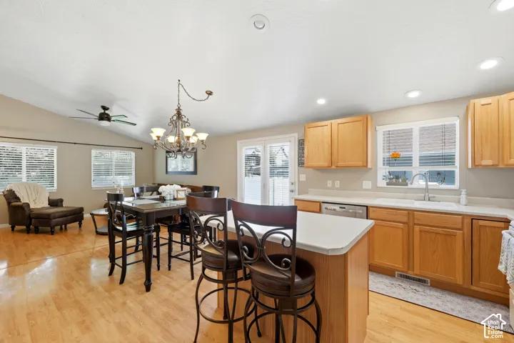 Open-concept kitchen and living area featuring wood-finish flooring, vaulted ceilings, and recessed lighting