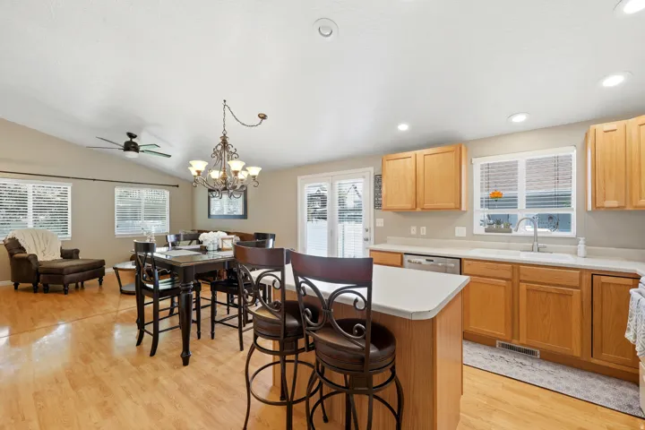 Open-concept kitchen and living area featuring wood-finish flooring, vaulted ceilings, and recessed lighting