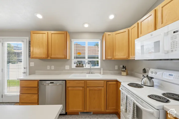 Kitchen featuring wood cabinetry, white countertops, stainless steel dishwasher, white range, and a dual basin sink