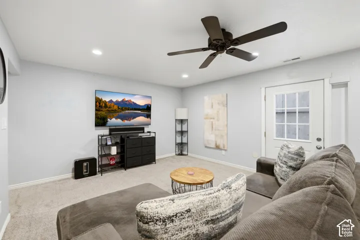 Carpeted living area featuring recessed lighting, a ceiling fan, and a white paneled door with windowpanes