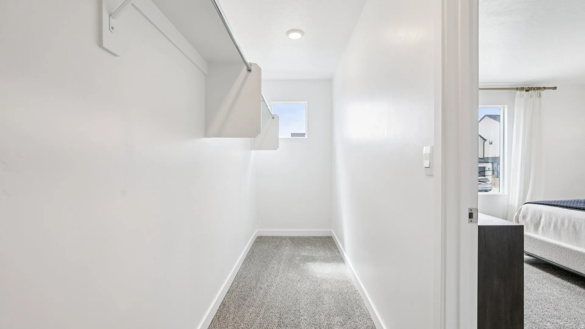 Walk-in closet featuring built-in shelving, hanging rod, recessed lighting, and a window