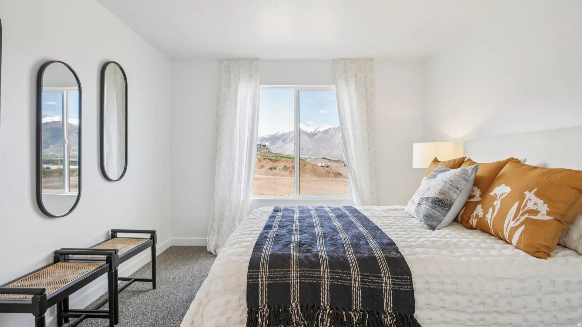 Bedroom featuring a large picture window with mountain scenery, white walls, and carpet flooring
