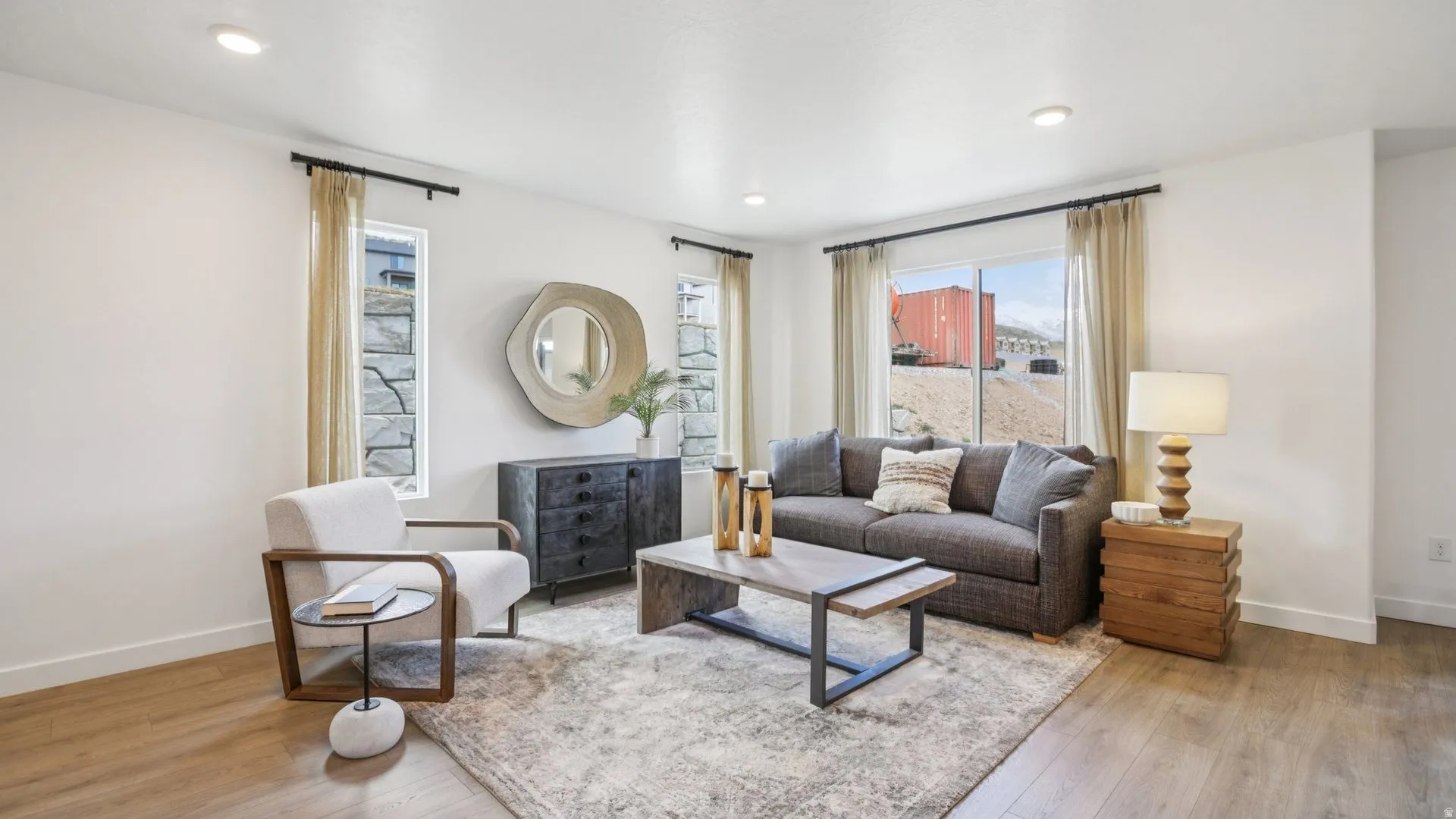 Spacious living area featuring light wood-finish flooring, recessed lighting, white baseboards, and expansive windows