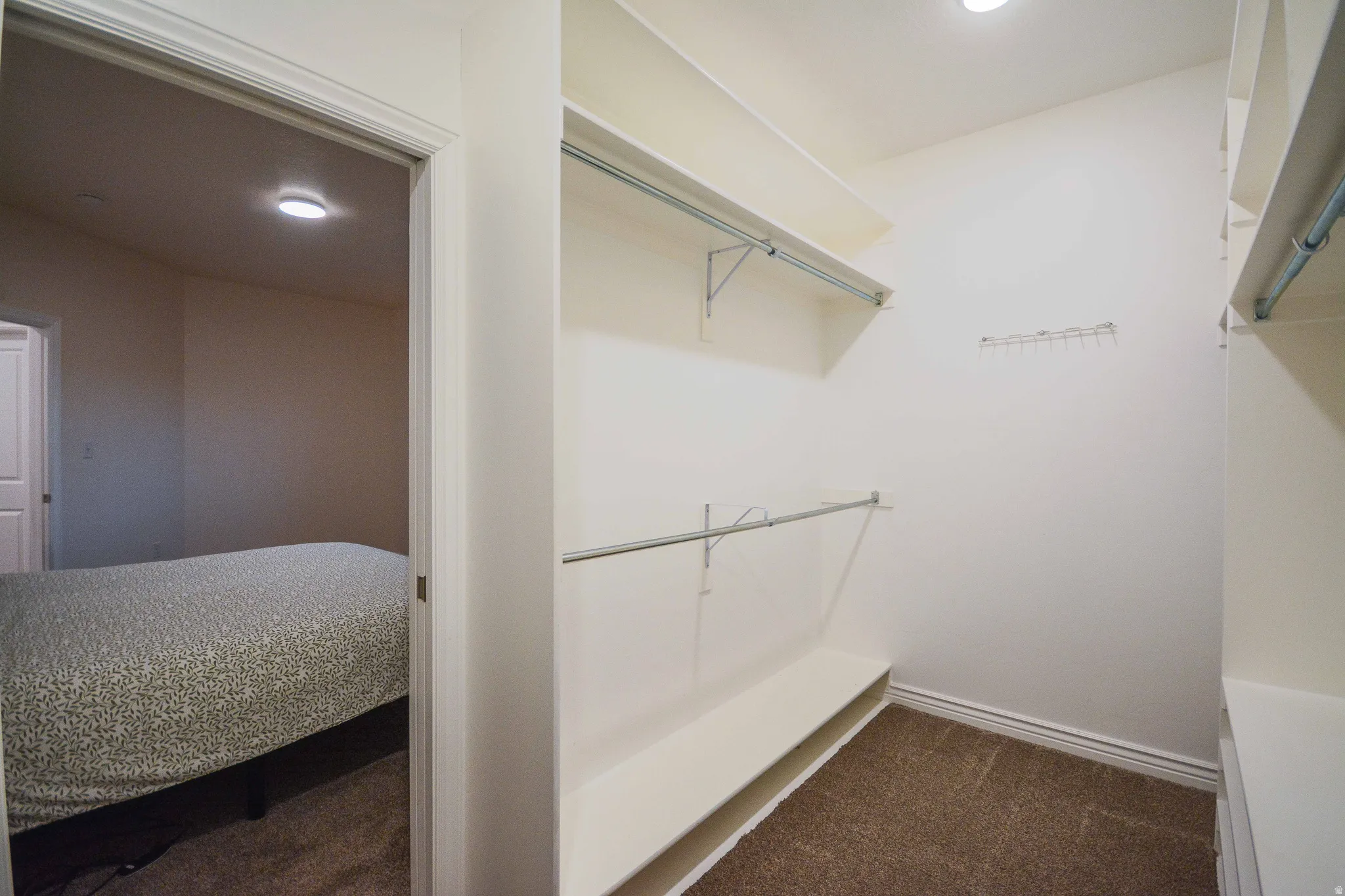 Walk-in closet featuring white built-in shelving, hanging rods, and recessed lighting